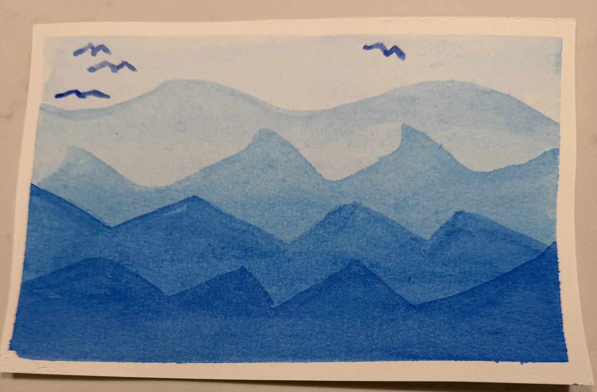 Student watercolour blue layered mountains with birds in flight