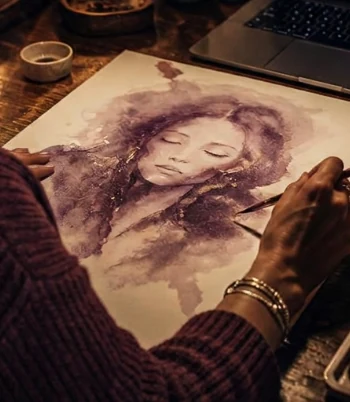 Anne-Marie painting an expressive aubergine and gold watercolour spirit portrait on handmade paper